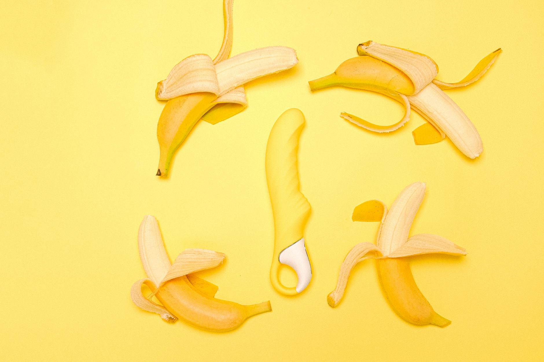 Yellow lemon-shaped clitoral vibrator on a yellow background surrounded by fresh lemons