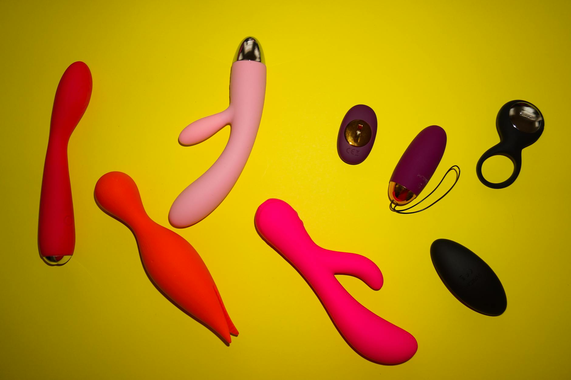 A collection of colorful lemon vibrators and clitoral toys arranged on a bright yellow surface