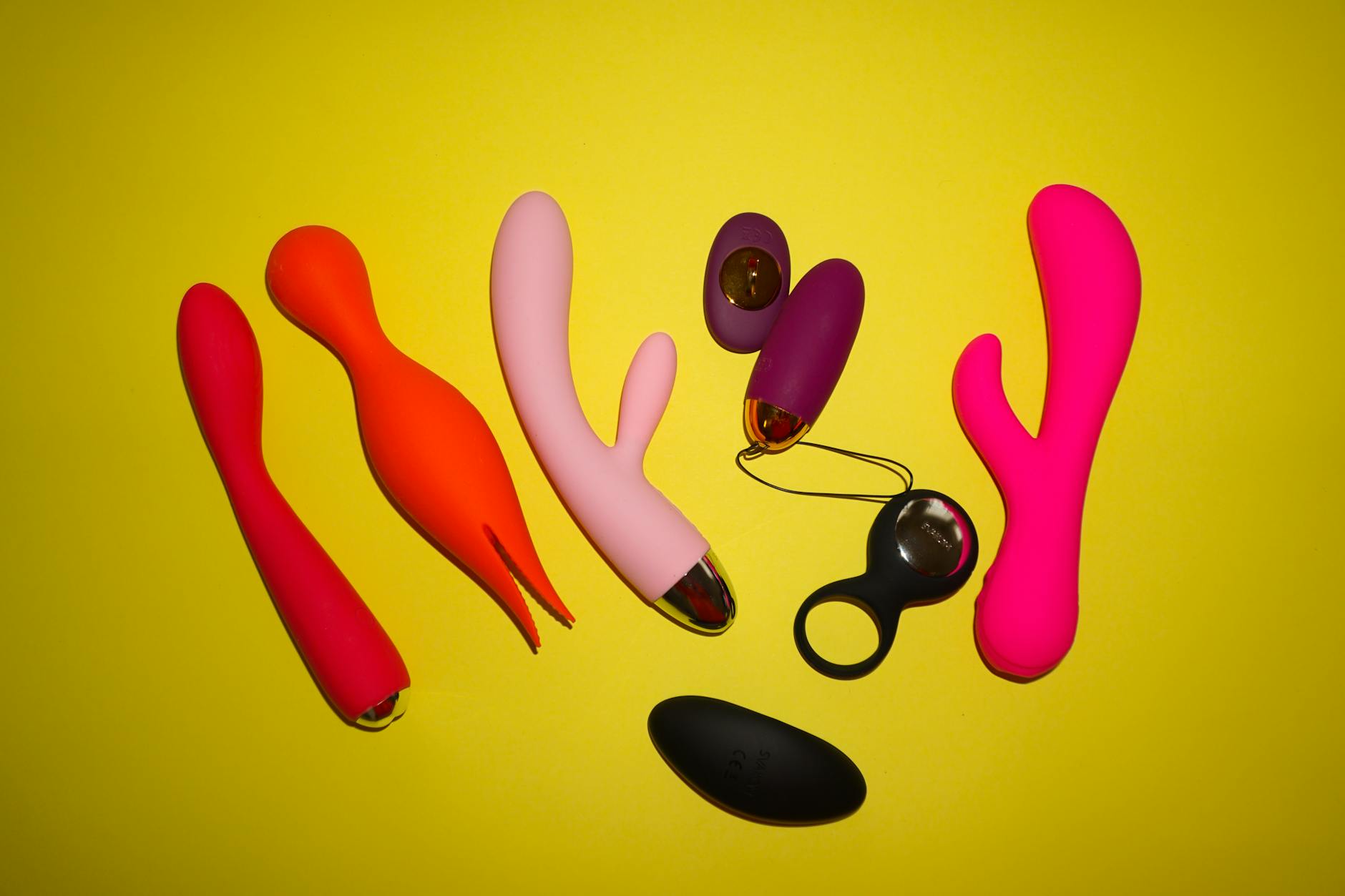Yellow silicone lemon vibrator surrounded by fresh citrus on a bright yellow background